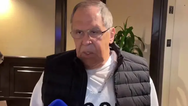 Sergei Lavrov speaking to reporters - wearing a white long-sleeved t-shirt and a gilet