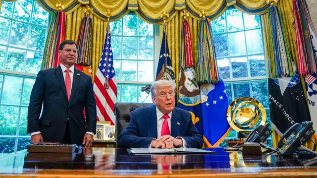 Trump in the Oval Office flanked by Social Security Administration commissioner Frank Bisignano