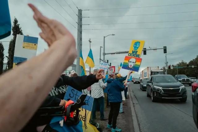 Protesters in Anchorage showing their support for Ukraine and holding placards with Putin's face that read "war criminal"
