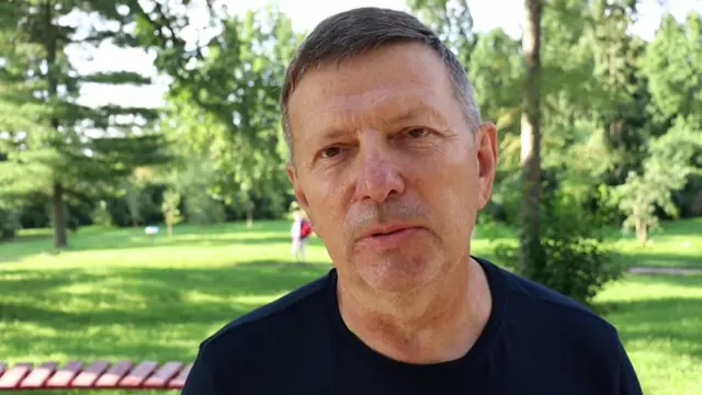 Man in black t-shirt stands in botanical gardens
