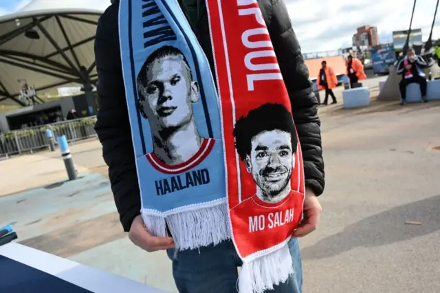 A supporter wearing a scarf with Erling Haaland and Mohamed Salah on it