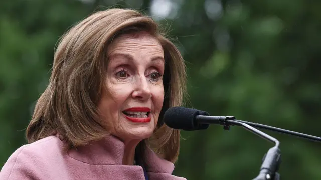 Nancy Pelosi speaks into a microphone on a podium.