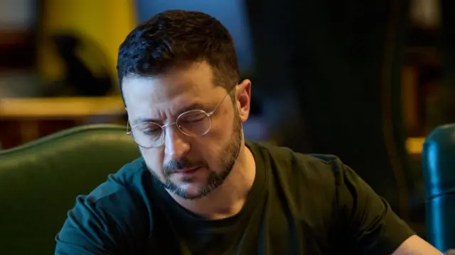 Volodymyr Zelensky sat at desk writing