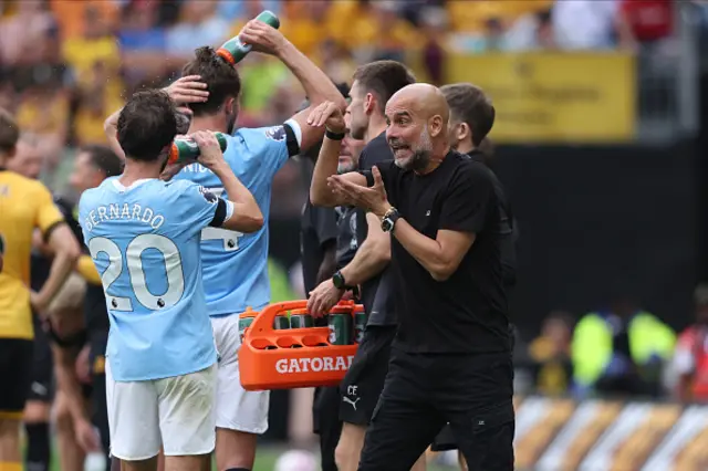 Pep Guardiola, Manager of Manchester City speaks to Bernardo Silva