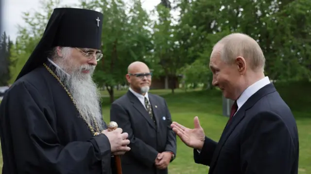 Russian President Vladimir Putin (R) talks to Archbishop Alexei (L) outside.