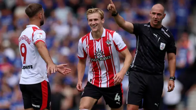 Referee Robert Madley speaks to Flynn Downes of Southampton