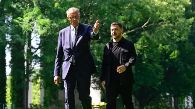 Ukrainian President Volodymyr Zelensky (R) and German Chancellor Friedrich Merz walk in the garden of the chancellery in Berlin to join a video conference of European leaders with the US President on the Ukraine war ahead of the summit between the US and Russian leaders,
