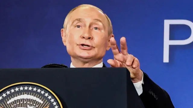 Russian President Vladimir Putin gestures during a news conference at a podium with the US emblem