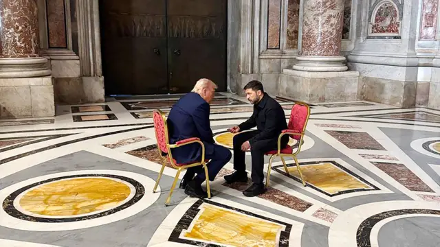 Donald Trump (L) and Volodymyr Zelensky (R) sitting together on matching red chairs inside St Peter's Basilica