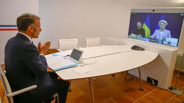 Macron speaks to a TV screen showing Zelensky and von der Leyen in a coalition of the willing meeting
