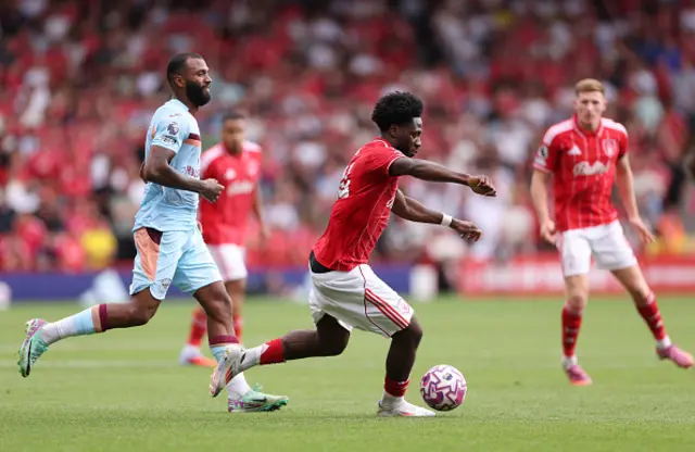 Ola Aina of Nottingham Forest runs with the ball whilst under pressure from Igor Thiago