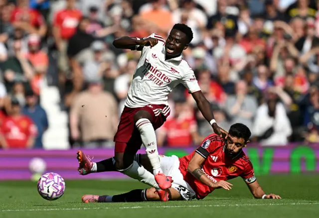 Bukayo Saka of Arsenal is challenged by Bruno Fernandes
