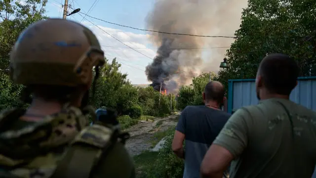 Ukrainian servicemen and residents observe houses burning and exploding amid a Russian air strike on August 14, 2025 in Sloviansk, Ukraine.