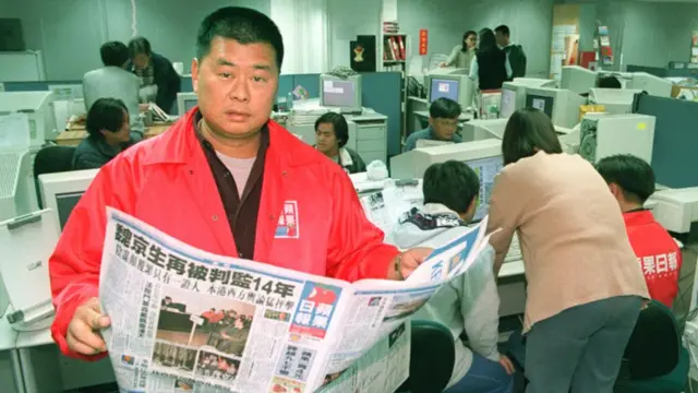 Lai, in a red jacket bearing Apple Daily's icon, in the newsroom in 1995