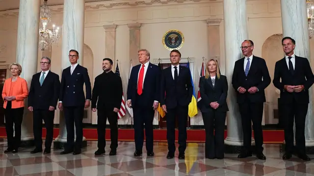 From left to right: Ursula von der Leyen in bright coral blazer; Sir Keir Starmer in black suit; Alexander Stubb in black suit; Volodymyr Zelensky in black blazer and trousers; Donald Trump in black suit; Emmanuel Macron in black suit; Giorgia Meloni in black blazer and trousers with white shirt; Friedrich Merz and Mark Rutte, both in dark suits