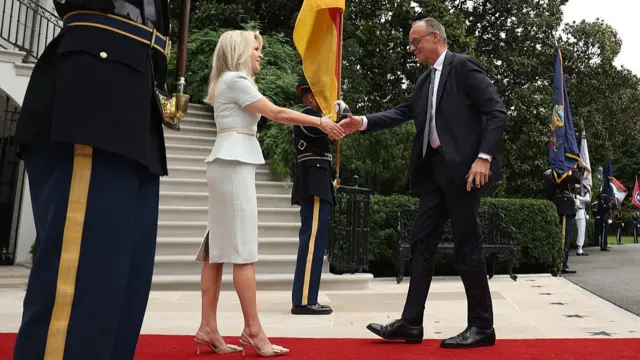 German Chancellor Friedrich Merz (R) is greeted by US Chief of Protocol Monica Crowley as he arrives at the White House