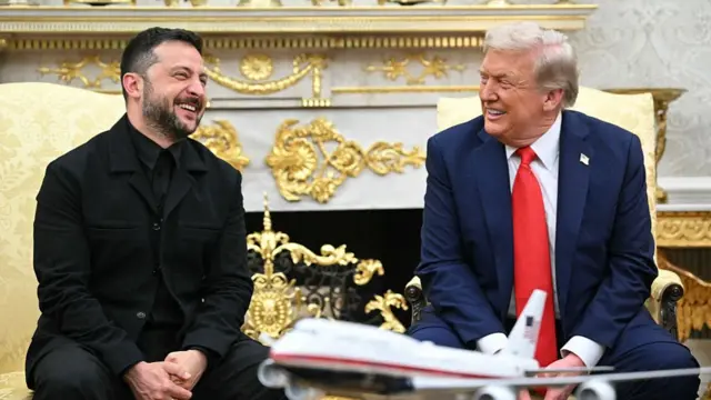 Trump and Zelensky smile as they sit next to each other in the Oval Office