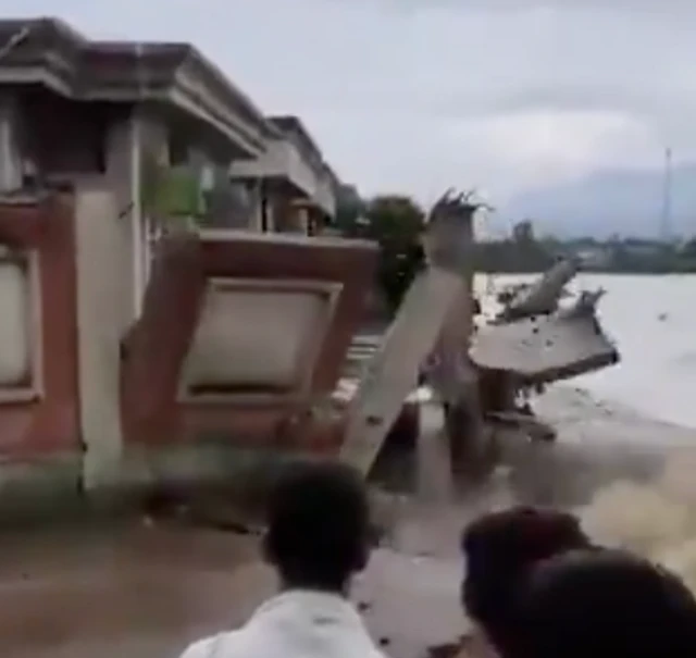 A group of people watching as a wall collapses into a river
