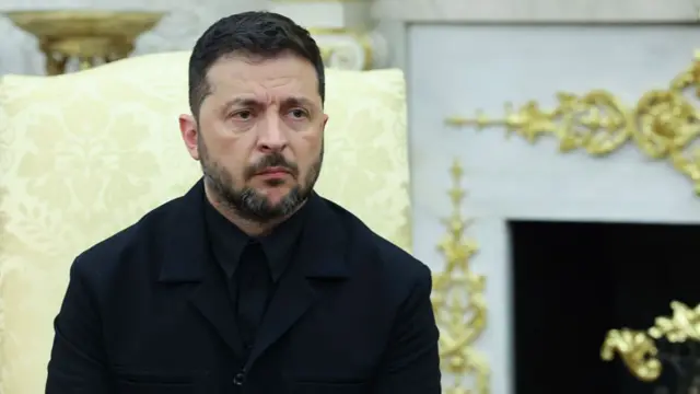 Zelensky wearing a black suit in the Oval Office