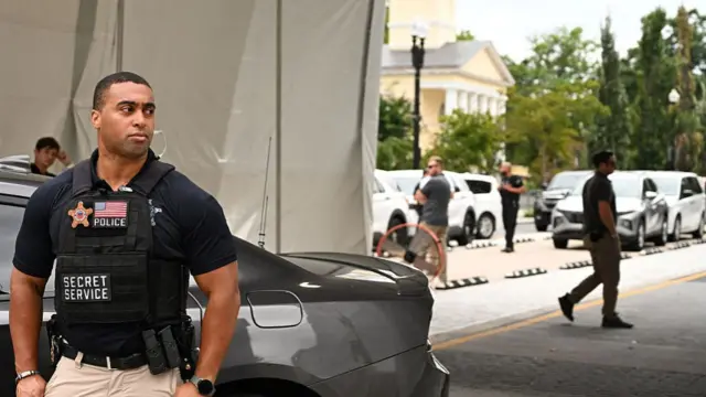 A secret service agent stands next to a car