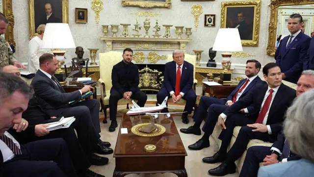 Zelensky and Trump seated in the middle of the Oval office, surrounded by other officials