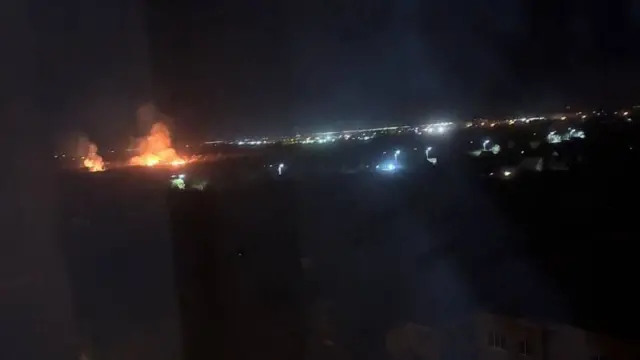 A picture taken at night with a large fire in the background