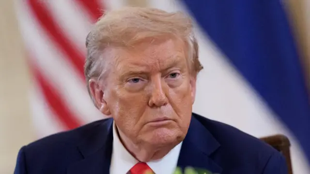 United States President Donald Trump wearing a navy suit and red tie
