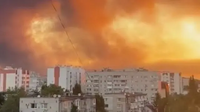 Dark smoke producing an orange hue hangs over high-rise buildings in the Ukrainian city of Kremenchuk