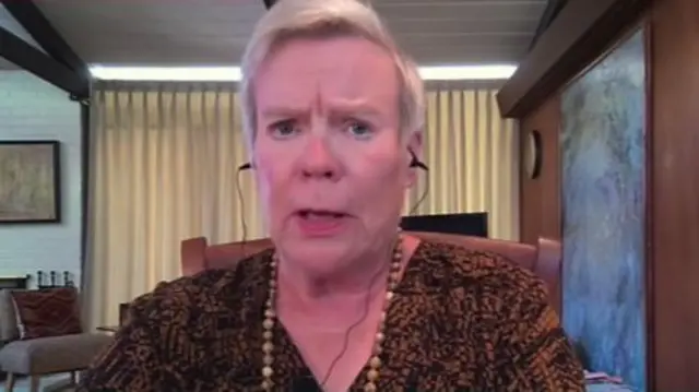 Goettemoeller looking at the camera during her television interview, wearing black wired earphones