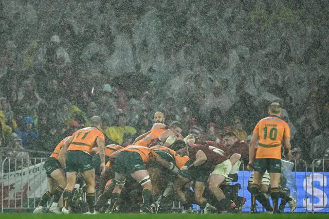 Australia and British & Irish Lions packs engage in a scrum amid heavy rain