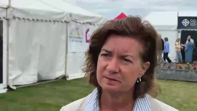 eluned Morgan, who has short brown hair, wearing a beige blazer and striped blue and white collar
