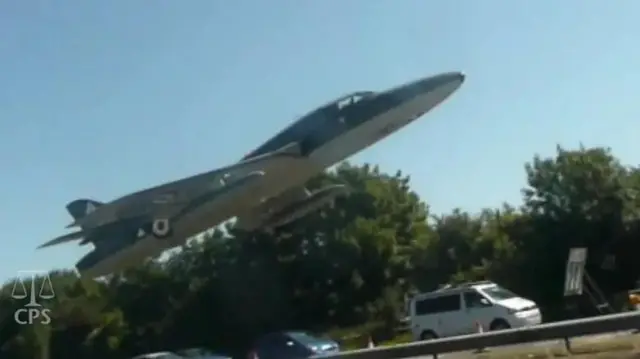 A jet plane metres above a road with cars on it