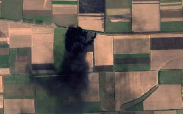 Black smoking rising from fields as viewed from above