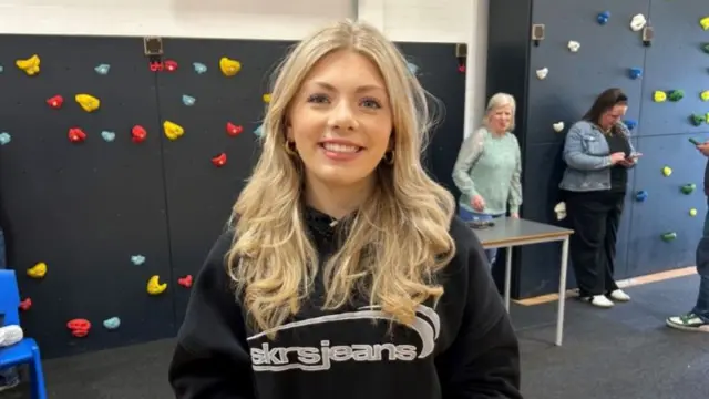 Gracie stood in front of a climbing wall