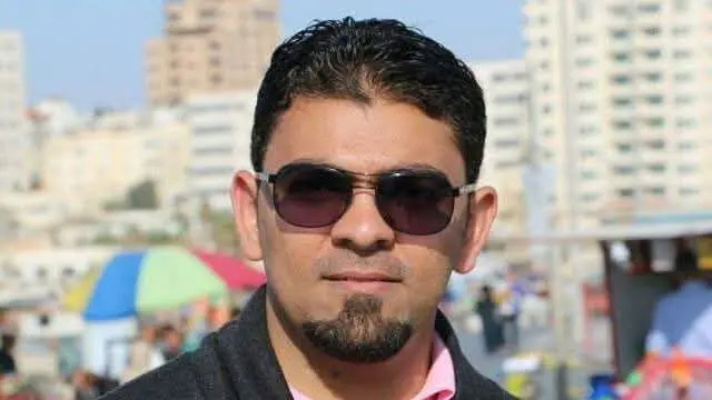 A Gazan man looks at the camera while wearing sunglasses.