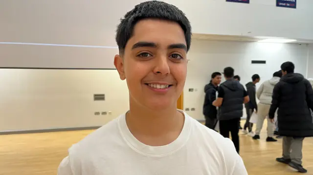 Mohammad smiling at the camera, wearing a white t-shirt