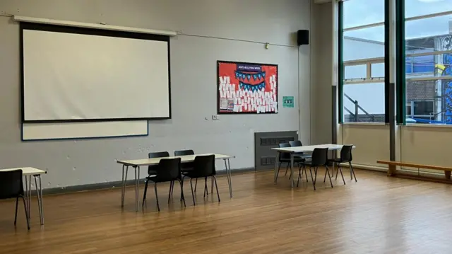 An empty school hall with a set of desks and chairs lined up ready for students to arrive for results day