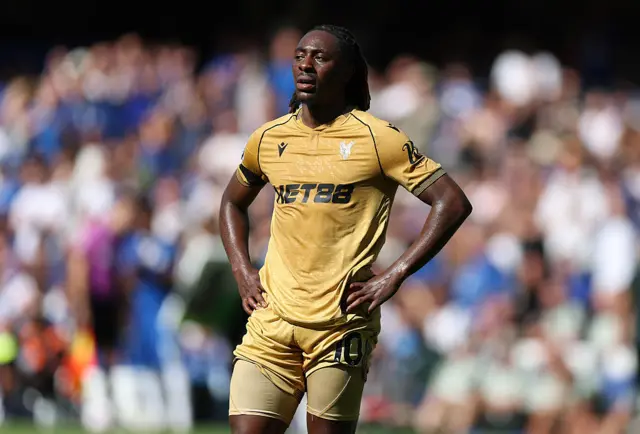 Eberechi Eze stands on the pitch at Stamford Bridge