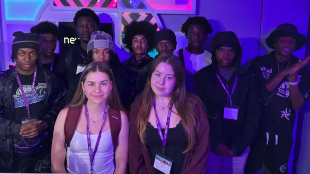A group of young people stand in a radio studio, the lighting is purple