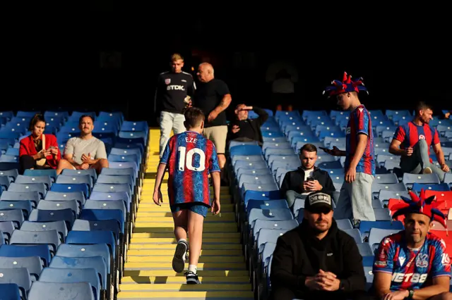 A Young fan walks up the stairs to his seat with an Eze 10 shirt