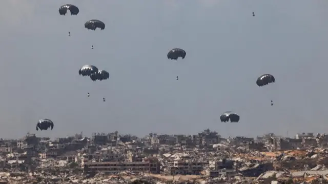 Aid packages can be seen parachuting into the Gaza Strip - which is characterised by fallen buildings and rubble