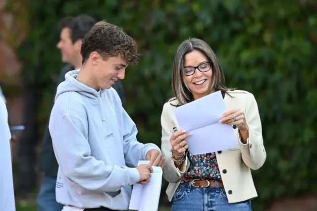 A pupil smiles as he opens his results outside