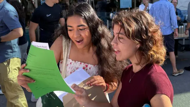 Two female students look carefully at their results on a piece of paper