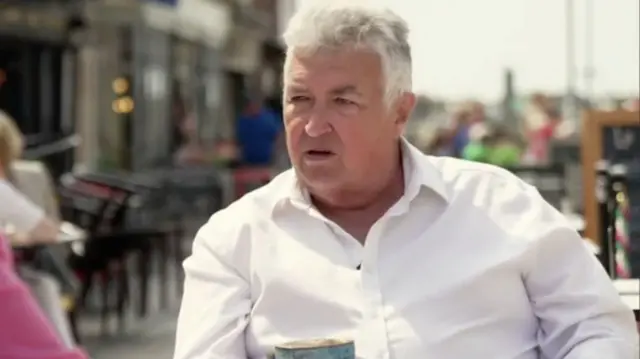 Neil Parkin, former leader of Adur District Council, in an open necked white shirt sat outdoors