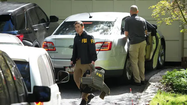 FBI agent carries body armour vest outside Bolton's home