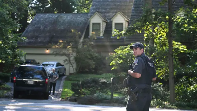 A police officer stands with back turned outside John Bolton's home