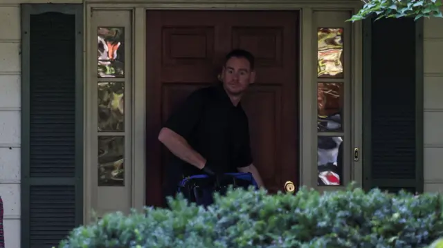 John Bolton's wife leaves house while FBI officer stands in doorway