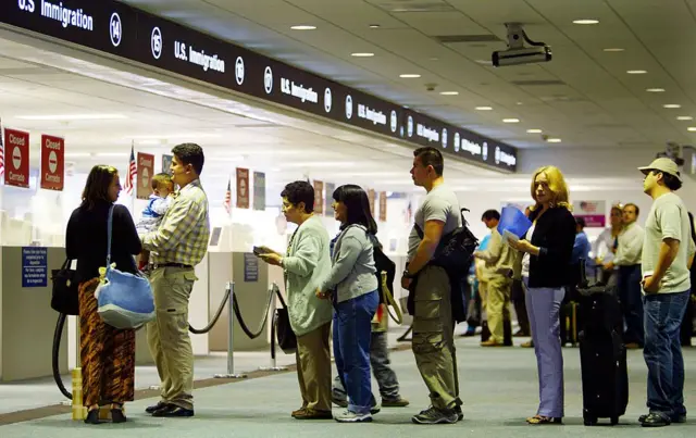 People wait to have their passports checked by immigration officials at a US airport