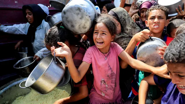 Crowds of children hold pans while waiting for aid in Gaza