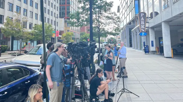 A group of journalists gathered outside Bolton's office building